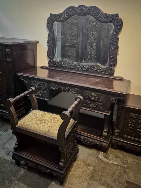 Antiga Penteadeira com banqueta, em madeira nobre, com entalhes ornamentados com figuras fitomórficas, com características que remetem ao estilo manuelino, com duas gavetas em cada uma das laterais. Dimensões: : 160 cm X 137 cm X 49 cm; Banqueta: 73 cm X 63 cm X 36 (Alt./Comp./Larg.). Parte inferior apresenta rachaduras na madeira. RETIRADA COM AGENDAMENTO PRÉVIO POR CONTA DO ADQUIRENTE OU TRANSPORTADORA INDICADA, EM CASA TÉRREA DA LAPA, RIO DE JANEIRO/RJ, IMPRETERIVELMENTE ATÉ O DIA 18.11, DATA DA ENTREGA DAS CHAVES DO IMÓVEL VENDIDO.