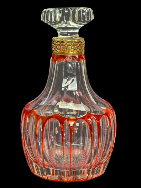 Belíssima Licoreira, em cristal doblê vermelha europeia, possivelmente Baccarat, lavrada com dedão, com estrela na base, tampa facetada em cristal em roseta, gargalo em bronze, ricamente cinzelado. Dimensões: 24 cm X 14 cm (Alt./Diâm.). Imperceptíveis bicados na oateral. d