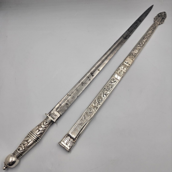 DOMINGOS DE MEO - SÃO PAULO - CUTELARIA PAULISTA - GRANDE FACA DE SOROCABA / SOROCABANA OU PUNHAL DE CORONEL - Grande, antiga e raríssima faca paulista, com bainha e empunhadura em prataria paulista. Produzida no início do Século XX, na oficina do renomado cuteleiro e importador Domingos De Meo. Lâmina "Extra-longa" importada, provavelmente de "Solingen", Alemanha, não apresenta sinais de uso. Em bom estado de conservação, conforme fotos. Marca do cuteleiro "De Meo S. Paulo" próximo a empunhadura. Bainha em prata lavrada, decorada com folhas e flores em alto e baixo relevo. OBS.: A bainha apresenta 3 anéis lisos, possivelmente de restauro. Agarradeira apresenta monograma "A.M" do antigo proprietário. Cabo em prata fundida segue a mesma decoração da bainha.  Não foi encontrado punção e nem garantia de teor da prata, entretanto foi verificado pelo toque do reagente. Até a presente catalogação, não foi encontrado nenhum exemplar ou citação na literatura especializada em faca paulista desta dimensão e aparelhada de prata, normalmente as facas são menores. Medidas (Faca): 60cm; (Bainha): 49cm; (Lâmina): 46cm; (Total): 62,5cm. INFORMAÇÕES SOBRE ELE: Domingos de Meo nasceu em 1874 na pequena cidade de Campobaso, no Sul da Itália, e já aos 18 anos veio para a cidade de São Paulo acompanhado do irmão José, inicialmente ambos trabalhando como cuteleiros contratados. No dia 20 de dezembro de 1895, aplicando suas pequenas economias, o jovem Domingos de Meo conseguiu abrir uma modesta oficina de cutelaria no centro da cidade, dedicando-se, juntamente com o irmão José, a produzir facas e a reformar e afiar tesouras, navalhas e assemelhados. Nessa época no Estado de São Paulo o tipo preferido de faca artesanal para defesa, na realidade um "punhal", era aquele denominado de franqueira (por ter surgido na cidade de Franca) ou aparelhada de prata (por ter a empunhadura e bainha nesse metal), com o característico terminal da bainha no formato de viola. Em poucos anos a fama do artesão ultrapassou as fronteiras de São Paulo e eram frequentes pedidos de clientes de outros Estados, principalmente aqueles de classes mais abastadas que podiam pagar os altos preços da época para facas artesanais elaboradas. Depois de 12 anos de árduo trabalho na pequena oficina, finalmente em 1907 Domingos ampliou seu negócio para um grande loja na Rua São Bento, 546 (endereço posteriormente renumerado para 38), também no centro da Cidade de São Paulo, onde dividia as tarefas com seus filhos adolescentes. (Informações tiradas no artigo da pagina "Paulistânia Tradicional", publicado em 13 de julho de 2020)