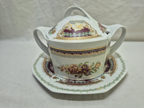 Linda sopeira com 2 alças, tampa e presentoir em porcelana Tcheca, ricamente decorada com friso ouro. Medindo a sopeira 19cm x 11cm de altura.