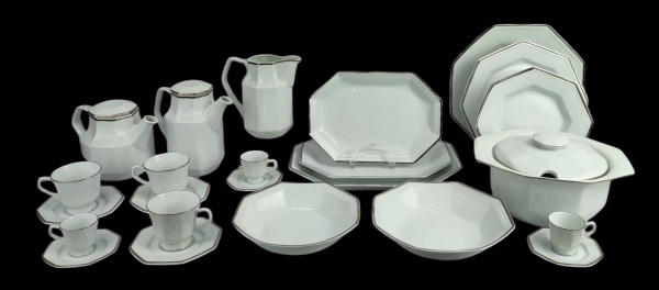 Aparelho para jantar, chá e café em porcelana Schmidt, com faixas prateadas, composto de sopeira, saladeira, legumeira, prato para bolo, 3 travessas, 2 bules, leiteira, 6 pratos rasos, 6 fundos, 6 para sobremesa, 6 xícaras para chá e 11 para café. Dois pratos fundos, um prato para sobremesa com bicado na borda e uma xícara de chá com fio de cabelo. Total de 45 peças. Med. sopeira 15x27,5x23cm.