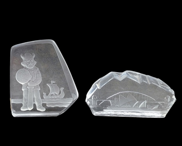 Duas placas em cristal, sendo uma tcheca, lapidações de guerreiro e barco e a outra assinada, possivelmente sueca Orrefors, lapidada com ponte e barco. Alts. 12cm e 7cm.