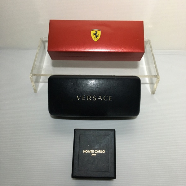 Lote com dois estojos, um da marca Versace para óculos e o outro da marca Ferrari para caneta e estojo Monte Carlo para brincos. Pequenos sinais de uso.