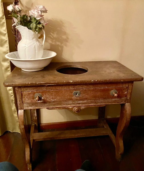 Rara mesa com abertura para gomil, em madeira nobre, com gaveta de 3 divisões, sendo uma exatamente para o fundo do gomil, com puxadores de época, medindo 73 cm altura x 48 profundidade x 88 largura. Acompanha o Gomil com sua bacia em porcelana branca decorada. Século XVII/XVIII.