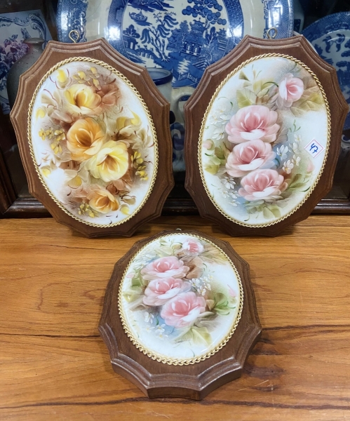 Três delicados quadros de parede, com medalhões de porcelana pintada a mão. Moldura em madeira. Altura do maior: 21x16cm.