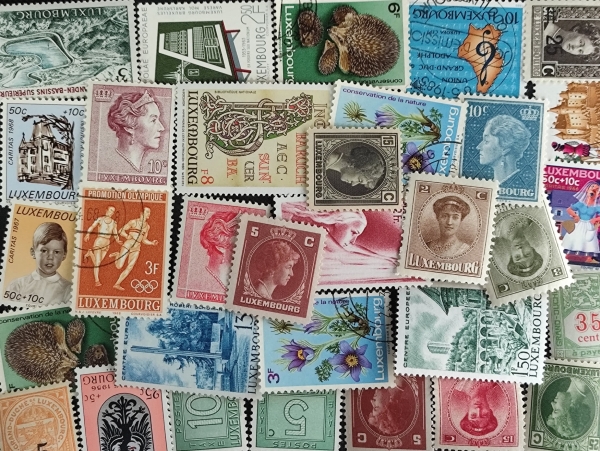 Lote de selos de Luxemburgo com diversos temas, incluindo personalidades, natureza, esportes e arquitetura, apresentando exemplares dentados com alguns carimbos visíveis.