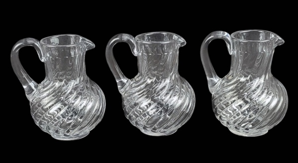 Três jarrinhas em cristal europeu, possivelmente francesas da Cristallerie Baccarat, decoradas com lapidações de gomos em relevo. Uma com lascadinho na base. Alt. 12,5cm.