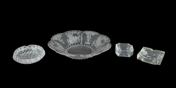 Quatro peças, sendo centro de mesa em vidro americano, com lapidações florais e 3 cinzeiros em cristal, de diversos modelos. Med. do centro de mesa 6,5x33cm.