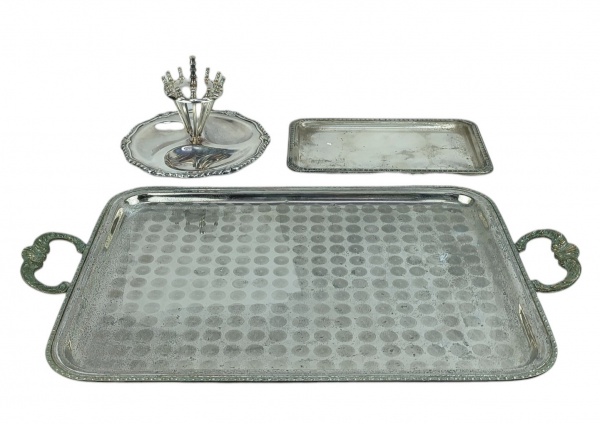 A) Petisqueira, com 12 espetos em metal prateado, marca da manufatura Eberle. Med. 13x20,5cm.B) Duas peças em metal prateado, sendo bandeja com alças trabalhadas em folhagens e volutas e bandejinha para rocambole, com gomos e conchas em relevo. Apresentam desgastes no prateado. Meds. 56,5x33,5cm e 26,5x16cm.