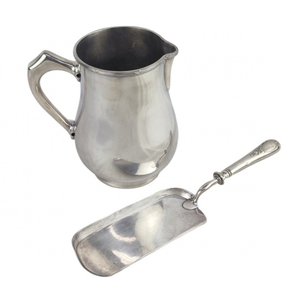 Duas peças em metal prateado, sendo pá cata migalha francesa, com marca da manufatura Christofle e jarra com marca Fracalanza. Comp. cata migalha 32,5cm. Alt. jarra 18,5cm.