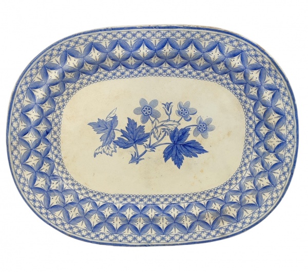 Travessa de coleção em faiança inglesa, com marca da manufatura, decoração floral e geométricos em tons de azul. Apresenta manchas causadas pelo tempo e fio de cabelo na aba. Med. 38,5x28,5cm.