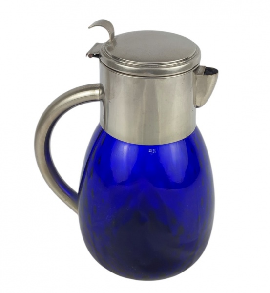 Jarra bojuda, em vidro na cor azul-cobalto. Guarnições em metal prateado. Apresenta discreto trincado abaixo do metal, visível somente por dentro. Alt. 26,5cm.