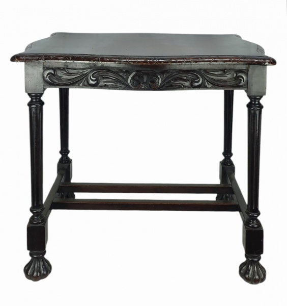 Elegante mesa de apoio em madeira, tampo recortado em ondulações com entalhes nas bordas, com volutas em baixo relevo e saia trabalhada em alto relevo. Pernas torneadas e frisadas unidas por travessões de seção quadrada. Pés em gomos. Tampa apresenta discretas marcas de uso. Med. 62x73,5x55,5cm.
