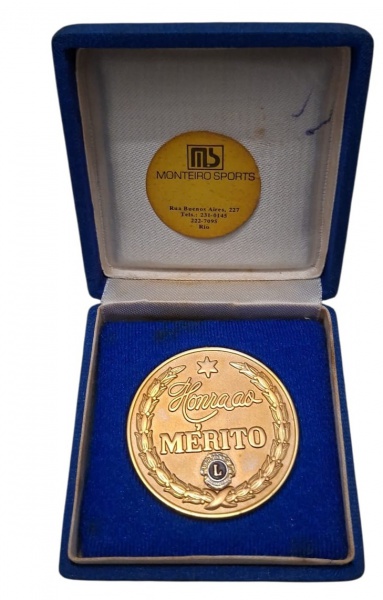 Medalha Honra ao Mérito Lions Club com estojo - Frente com inscrição "Honra ao Mérito", ramo de louros, estrela e emblema Lions Club Internacional - Estojo azul com forração azul veludo e etiqueta int