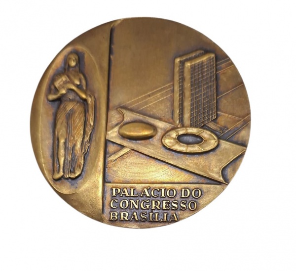 Medalha de bronze correr revestimento Dourado na parte central símbolo da República Federativa do Brasil em relevo no verso figura feminina segurando o livro e Palácio do Congresso de Brasília em rele