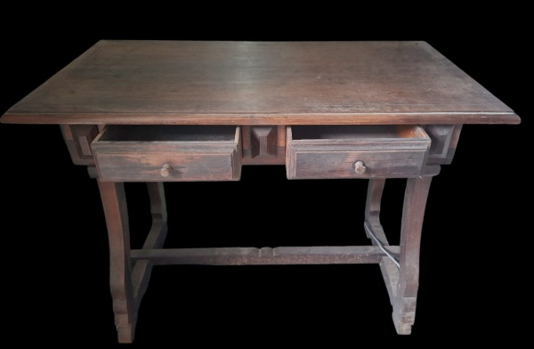 Escrivaninha/Mesa de Madeira Maciça com 2 gavetas - Parece ser jacarandá ou imbuia, pela cor escura, veta e peso visual. A patina e desgaste indicam peça antiga, provavelmente anos 40-70- Estrutura: P