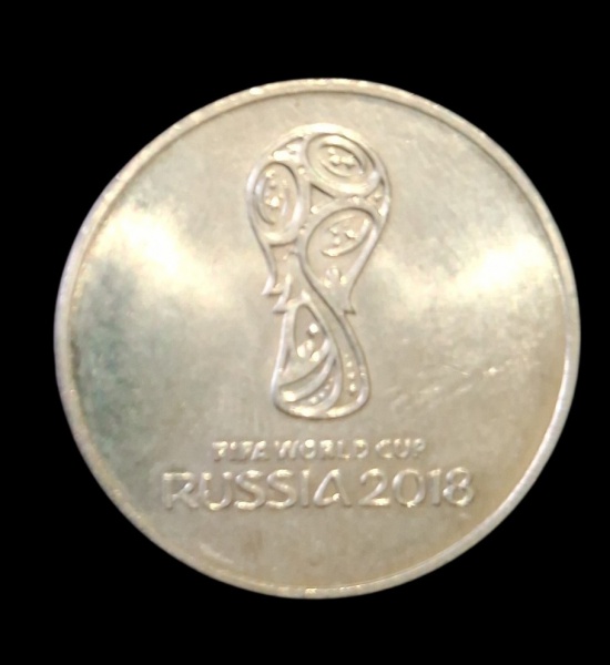 Numismática - Moeda Comemorativa - FIFA World Cup Russia 2018 - Item: Moeda metálica prateada com o logo oficial da Copa 2018. Texto "FIFA WORLD CUP RUSSIA 2018" + símbolo do troféu estilizado - Conte