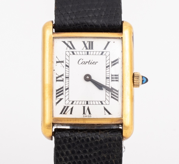 CARTIER TANK - Relógio suíço de pulso. Caixa em metal banhado a ouro, visor em acrílico. Mostrador branco com alagarismos romanos em preto. Movimento a corda. Pulseira original com sinais de uso em co