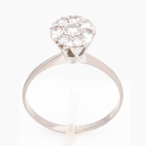 Anel "flor" em ouro branco, 18 K, cravejado com sete brilhantes de aproximadamente 7 pontos cada e um de aproximadamente 10 pontos. Aro 23. Peso 2,4 gr. (Por medida de segurança esse lote não se encon
