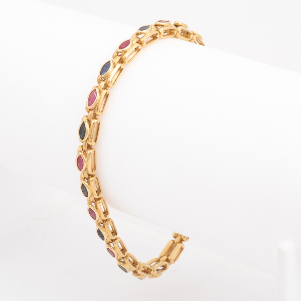 Pulseira em ouro amarelo, contrastado 750 K, cravejada com rubis e safiras lapidação navete. Med. aberta 19,5 cm. Peso 15,5 gr. (Por medida de segurança esse lote não se encontra em nossa loja).