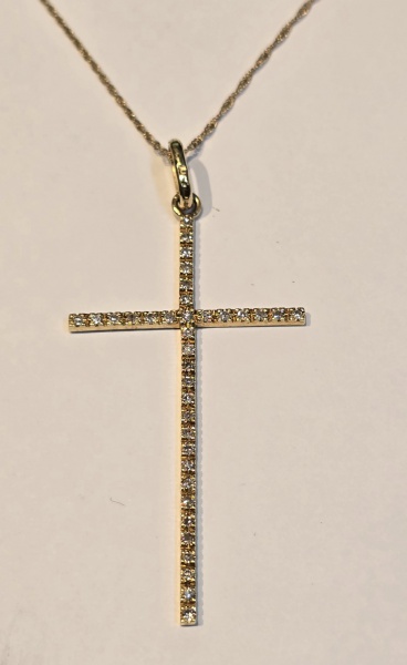 Cordão e pingente em forma de cruz, em ouro amarelo, contrastado 750 K. Pingente cravejado de diamantes. Med. Cordão aberto 46cm, pingente 5 x 2,6 cm. Peso 3.5 gr. (Por medida de segurança esse lote n