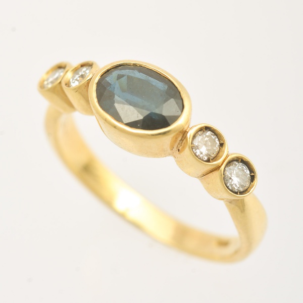Anel de ouro amarelo 18 k (750), com uma safira oval e dois brilhantes de cada lado. Peso 3,7 g. Aro 18