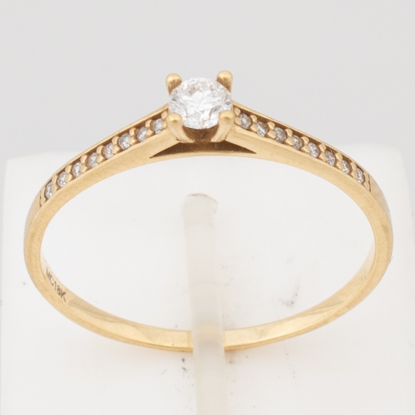 MONTE CARLO - Anel solitário em ouro amarelo, contraste 18 K e da joalheria. Brilhante de aproximadamente 15 pontos ladeado com dezesseis diamantes cor K-SI. Aro 21,5. Peso 1,7 gr. (Por medida de segu