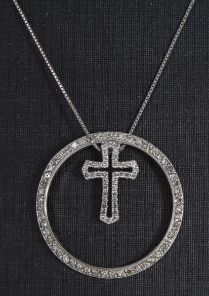 Delicado colar com pingente em ouro branco, contrastado 750 k e 18 k. Pingente em forma de cruz dentro de círculo cravejados de brilhantes. Med. cordão aberto 43 cm, pingente 2,3 cm diâm. Peso 4,2 gr.