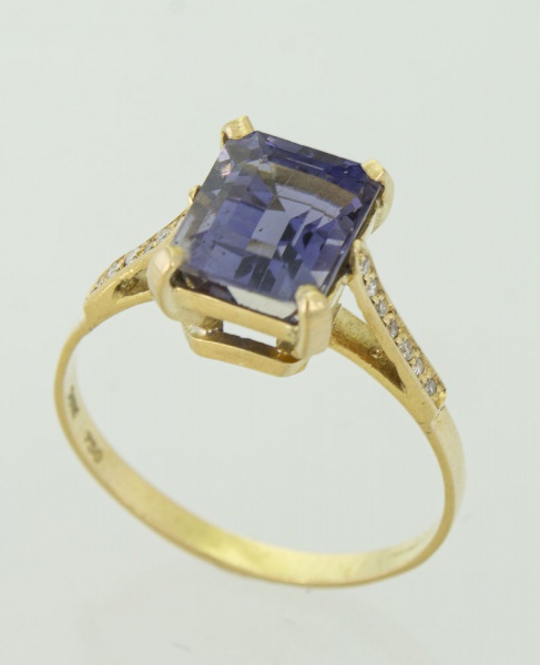 Anel em ouro amarelo, contrastado 750 k com tanzanita de aproximadamente 2 cts, ladeada por quatorze brilhantes de aproximadamente 0,5 pts cada. Aro 19. Peso 2,7 gr. (Por medida de segurança esse lote