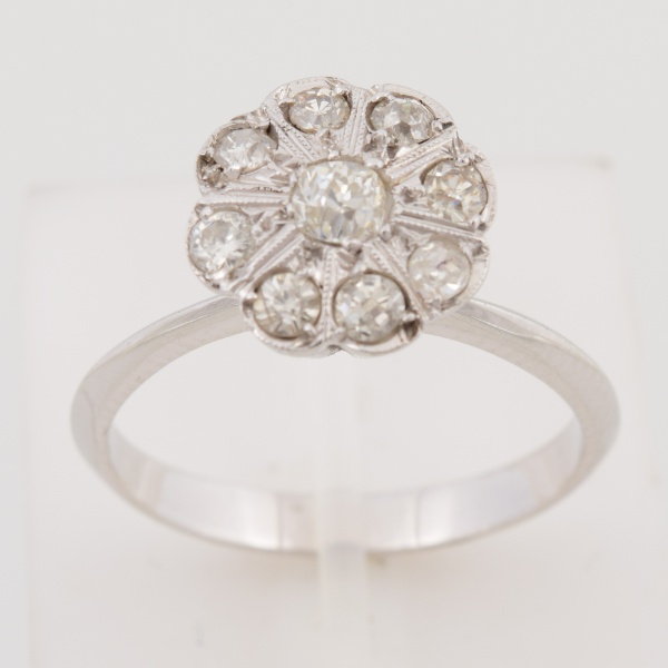 Anel "flor" em ouro branco 18k, cravejado com oito brilhantes de aproximadamente 4 pts e central de 10 pts. Aro 15. Peso 3,2 gr. (Por medida de segurança esse lote não se encontra em nossa loja).