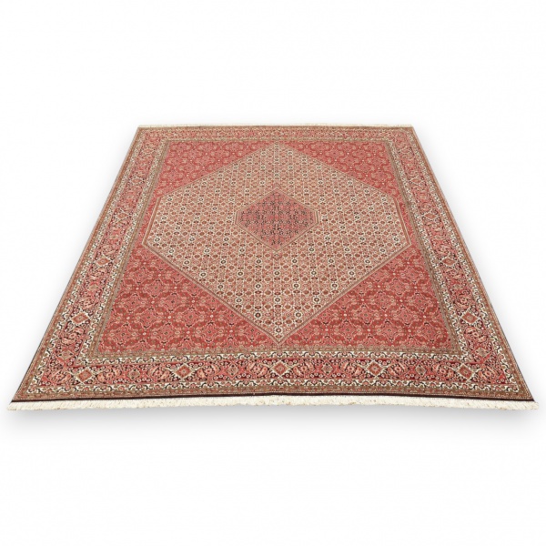 Tapete estilo persa com rica padronagem geométrica e floral em tons de vermelho, bege, azul e vinho, com medalhão central e franjas nas extremidades; medidas 4,00 x 2,96 m; apresenta marcas do tempo e