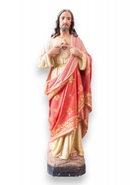 Escultura religiosa em gesso representando Sagrado Coração de Jesus, com policromia em tons de vermelho, rosa e bege, detalhes dourados nas vestes e base sextavada. Peça com marcas do tempo, desgastes