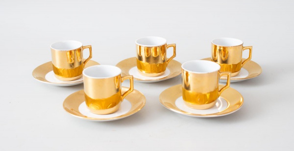 Conjunto de 5 xícaras de café com pires em porcelana Porcelana Mauá , revestimento externo em ouro brilhante espelhado e interior branco. Corpo cilíndrico com alça angular dourada e pires de aba larga