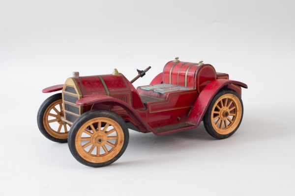 Carrinho antigo de brinquedo em metal e plástico na cor vermelha; medindo 30 cm de comprimento; peça com marcas do tempo, desgastes, oxidação e possíveis faltas; não testado; vendido no estado em que