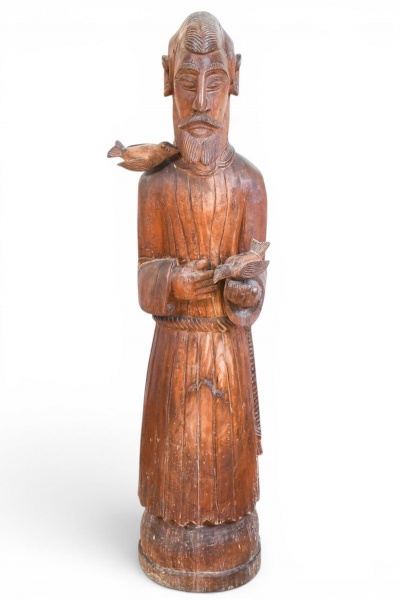 Escultura em madeira entalhada à mão representando figura religiosa com barba, manto longo e pássaros, assinada na base com o nome Sabino. Estilo popular de arte sacra, possivelmente de origem filipin