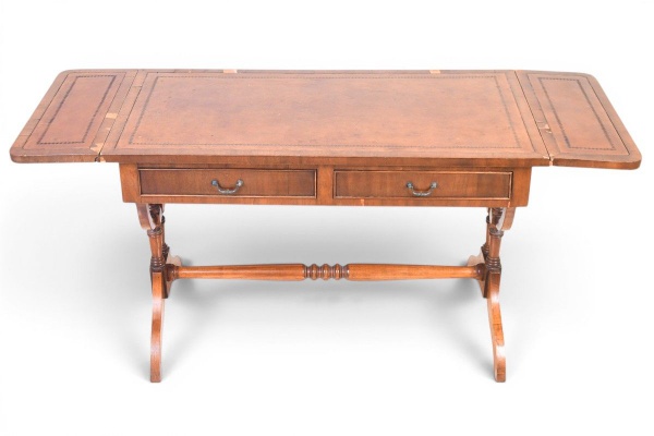 Mesa escrivaninha estilo Regência inglesa (sofa table) em mogno, séc. XIX, com tampo revestido em couro castanho gravado com filetes dourados, duas abas laterais rebatíveis, duas gavetas com puxadores