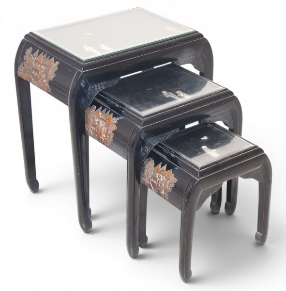 Conjunto de três mesas ninho chinesas em laca preta, estilo Chinoiserie, séc. XX, com tampos em vidro protegendo decoração em laca com figuras de personagens, paisagens e borboletas em relevo dourado