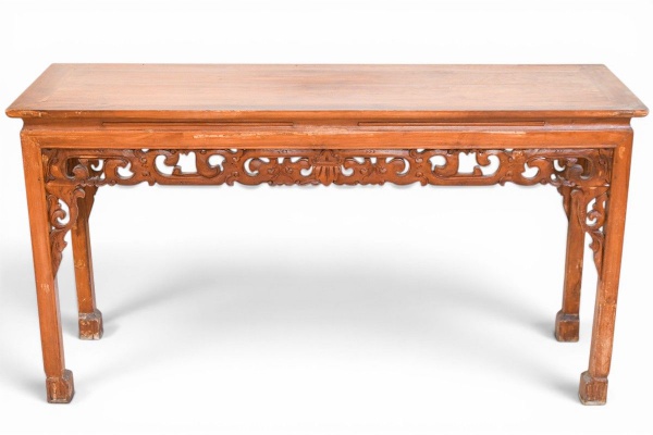 Mesa altar (altar table) chinesa em madeira de teca ou olmo, estilo período Qing, séc. XIX, com tampo de prancha única com bordas retas, saia frontal ricamente entalhada em motivos de ramos e volutas