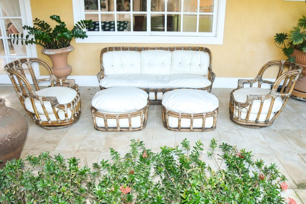Conjunto de varanda em rattan e bambu, estilo tropical colonial, séc. XX, composto por sofá de três lugares com estrutura em bambu entrelaçado com nós em fibra natural, duas poltronas de formato barri