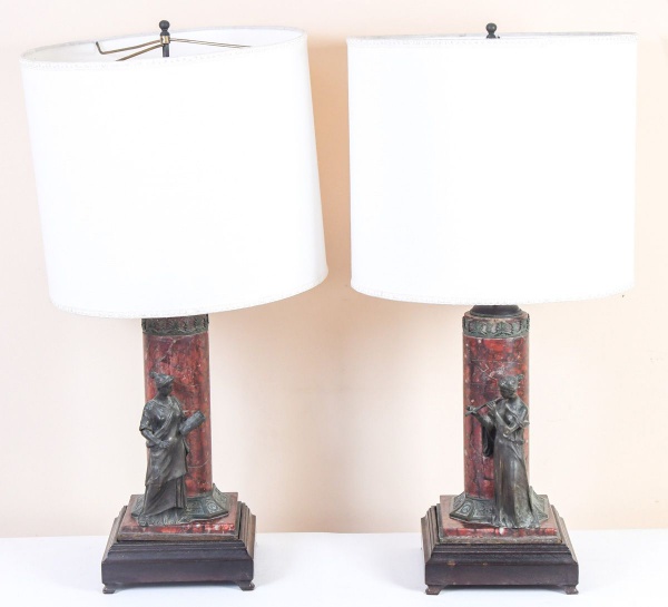 Par de abajures de mesa em estilo clássico, com colunas revestidas em mármore vermelho, aplicações em metal patinado representando figuras femininas e cúpulas em tecido claro, medindo aproximadamente