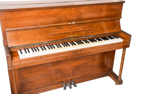 Piano vertical marca H. Brooks, em madeira nobre com acabamento em verniz, três pedais, medindo 108 x 138 x 54 cm; apresenta marcas de uso, desgastes, riscos, manchas e sinais do tempo; não testado, v
