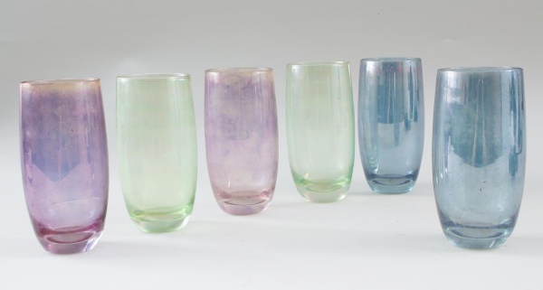 Lote contendo 6 copos em vidro iridescente colorido, sendo exemplares nas tonalidades verde, azul e lilás, com acabamento perolizado. Medindo 15 cm de altura. Peças com marcas do tempo, desgastes e si
