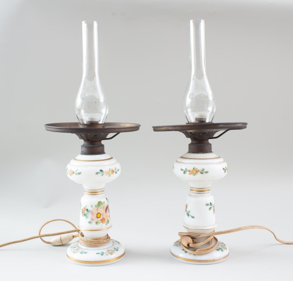Par de luminárias em porcelana decorada com motivos florais, com cúpulas de vidro tipo lampião, medindo 45 cm de altura; peças eletrificadas, não testadas, apresentam sinais de uso, marcas do tempo e