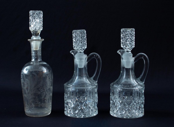 Lote contendo três licoreiras em cristal lapidado, com tampas originais facetadas, sendo uma com alça aplicada e outra com decoração gravada, medindo a maior 24 cm de altura; apresentam sinais de uso,