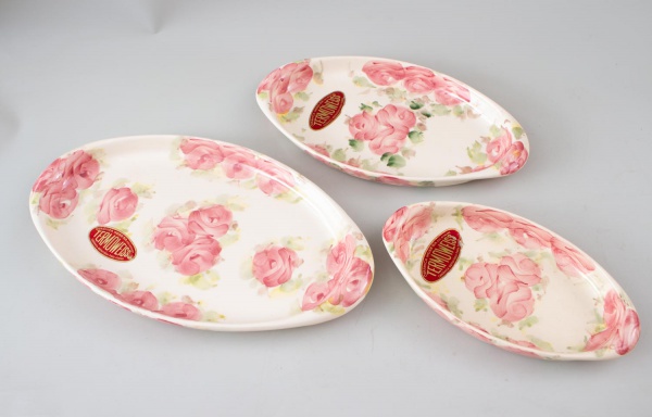 Lote contendo três travessas ovais em porcelana Weiss Brasil, decoradas com motivos florais em tons de rosa, medindo a maior 40 x 23 cm; apresentam sinais de uso, marcas do tempo e pequenos desgastes.