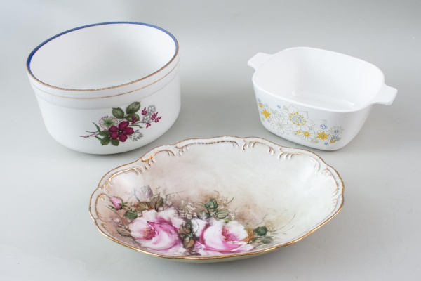 Lote contendo 3 peças, sendo uma travessa em porcelana Schmidt decorada com flores, uma travessa refratária Corning Ware e uma tigela em porcelana Procópio; apresenta marcas do tempo, desgastes e sina