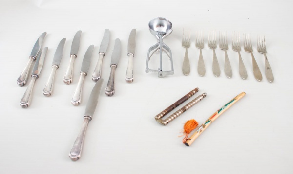 Lote contendo 9 facas inox com cabos ornamentados, 7 garfos de mesa, concha para sorvete, quebra-nozes metálico e canivete com cabo decorado. Peças com marcas do tempo, desgastes e sinais de uso, conf
