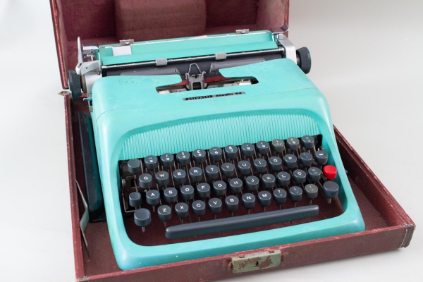 Máquina de escrever portátil Olivetti Studio 44, na cor verde, acompanhada de estojo de transporte original. Peça com marcas do tempo, desgastes e sinais de uso. Funcionamento não testado. Conforme fo