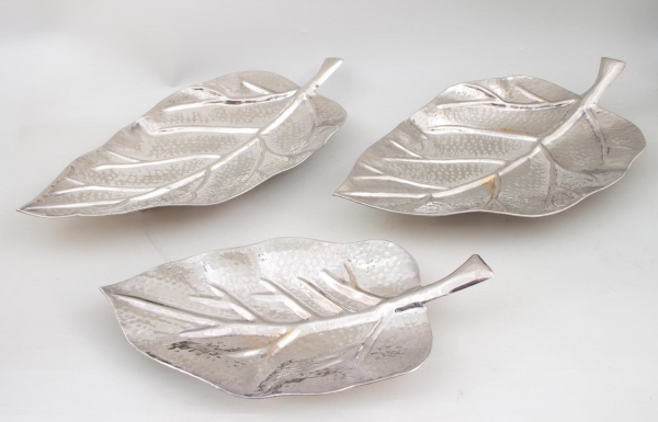 Lote com 3 efeites decorativo em formato de folha, em metal prateado martelado; tamanhos variados; apresentam sinais de uso, marcas do tempo, oxidação e pequenos desgastes.