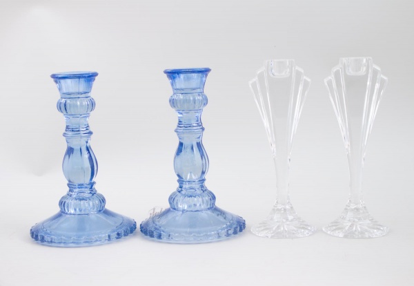 Lote contendo 2 castiçais em vidro azul e 2 floreiros em vidro incolor, medindo 18 cm de altura; apresentam sinais de uso e marcas do tempo.